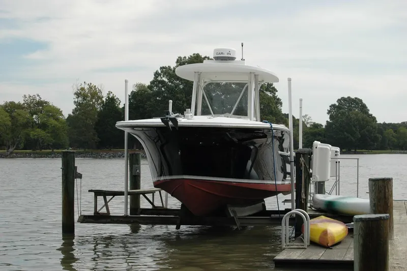 Slide: The Image of 2013 Composite Yacht 26 on lift at dock, surrounded by trees and water. - 2