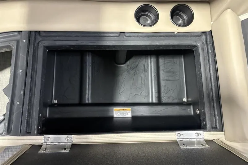 Slide: The Image of Storage compartment in 2026 Premier 220 Sunscape RF boat with cup holders and warning label. - 28