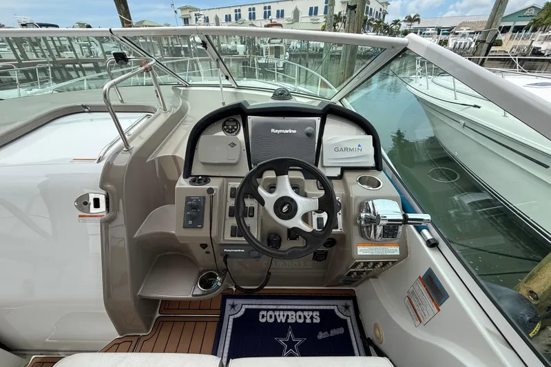 Slide: The Image of 2008 Cruisers Yachts 330 Express helm with steering wheel, navigation equipment, and marina view. - 17