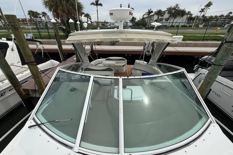 Slide: The Image of 2008 Cruisers Yachts 330 Express docked, showcasing cockpit and windshield, surrounded by palm trees. - 33