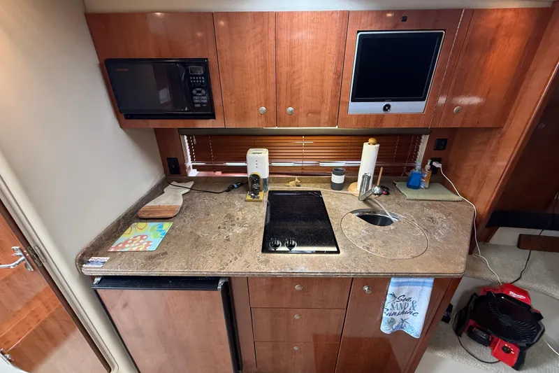Slide: The Image of 2008 Cruisers Yachts 330 Express kitchen with microwave, stove, sink, and wooden cabinets. - 41