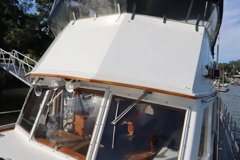 Slide: The Image of 1993 Grand Banks 46 Classic yacht, showcasing helm and windows, docked by the water. - 10