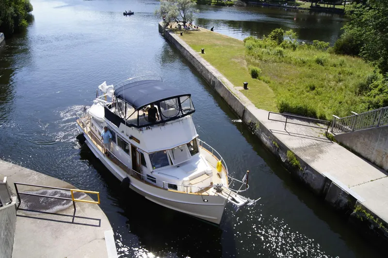 Slide: The Image of Grand Banks 42 Classic yacht navigating a narrow canal, surrounded by lush greenery. - 131