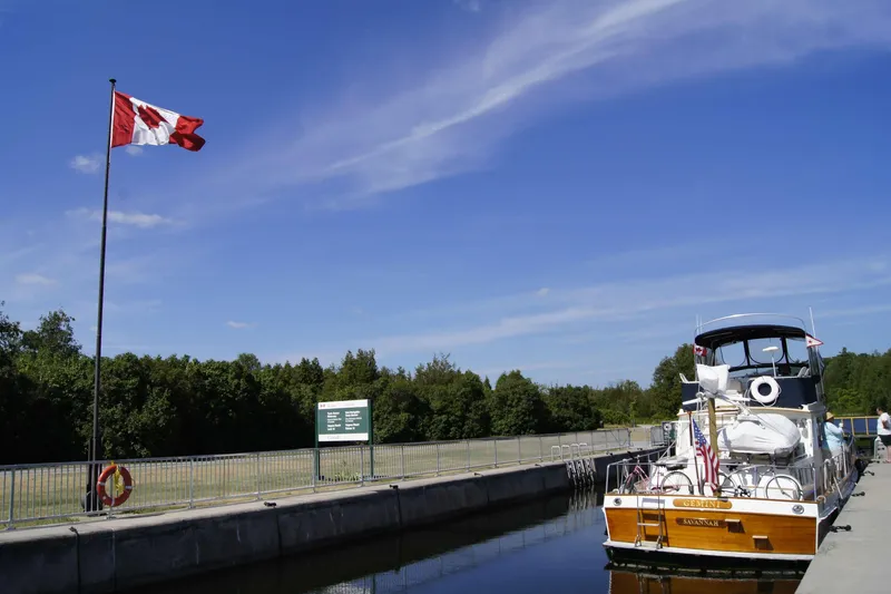 Slide: The Image of Grand Banks 42 Classic yacht docked near Canadian flag, clear blue sky. - 133