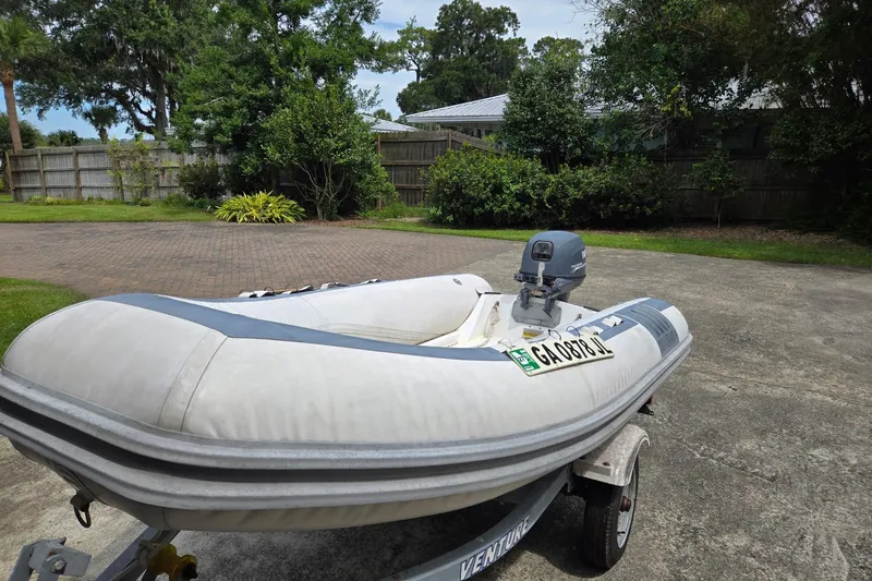 Slide: The Image of Inflatable boat on trailer in driveway, surrounded by greenery and trees. - 138