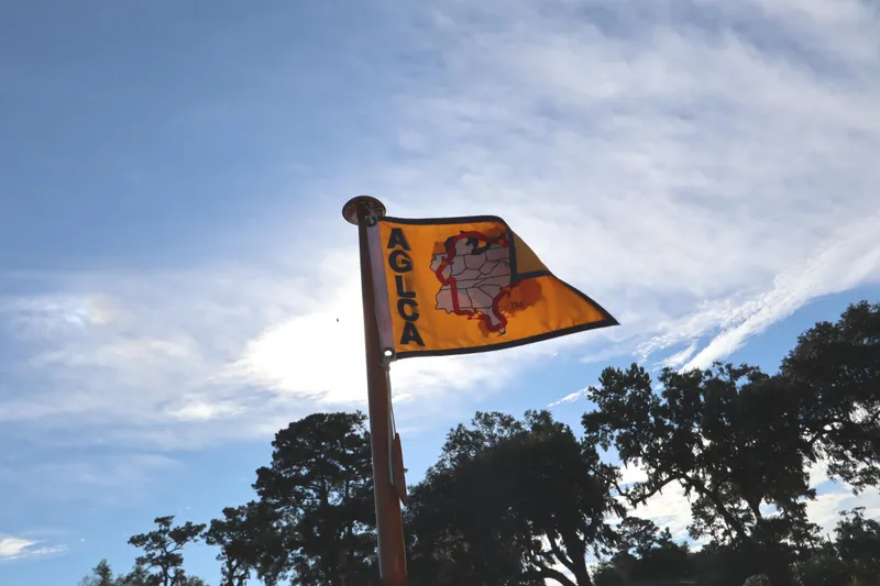 Slide: The Image of Flag with AGLCA logo waving against a blue sky, trees in the background. - 14
