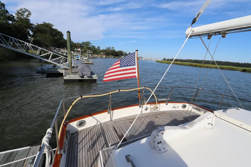 Slide: The Image of 1993 Grand Banks 46 Classic yacht with American flag on calm waterway. - 17