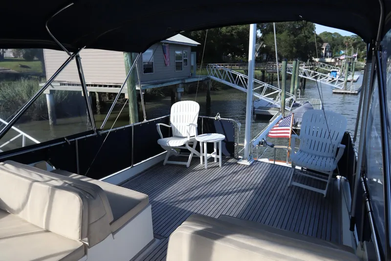 Slide: The Image of 1993 Grand Banks 46 Classic yacht deck with seating, docked near waterfront homes. - 23