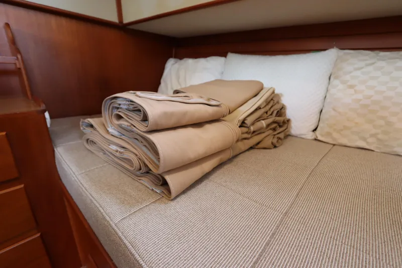 Slide: The Image of Folded beige linens on a bed inside a 1993 Grand Banks 46 Classic yacht. - 76