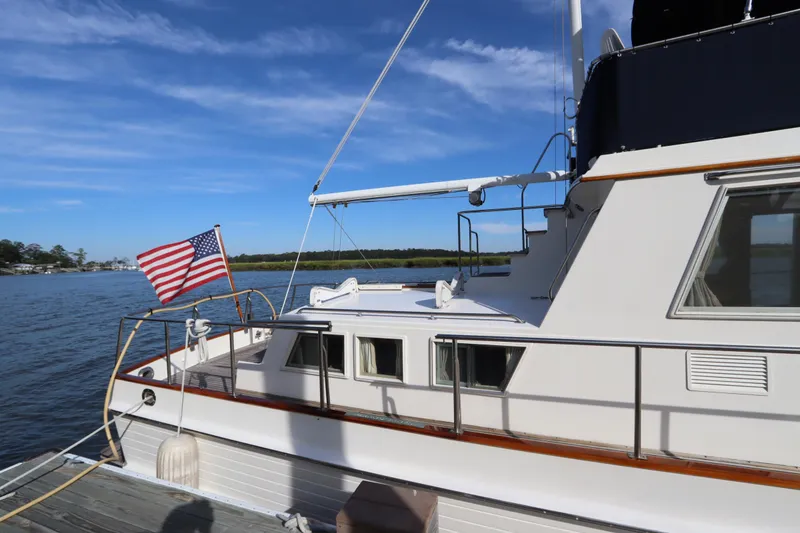Slide: The Image of 1993 Grand Banks 46 Classic yacht docked with American flag, under clear blue sky. - 8