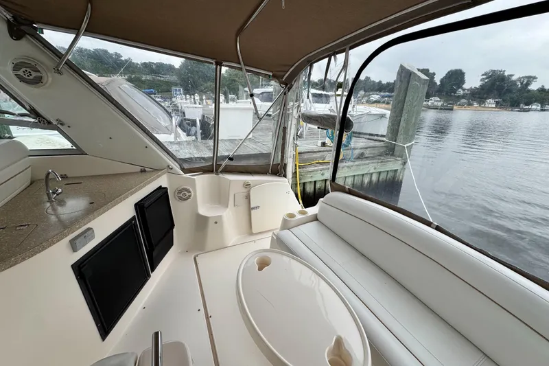 Slide: The Image of 2005 Rinker Fiesta Vee 342 boat interior with seating and kitchenette, docked by the water. - 14