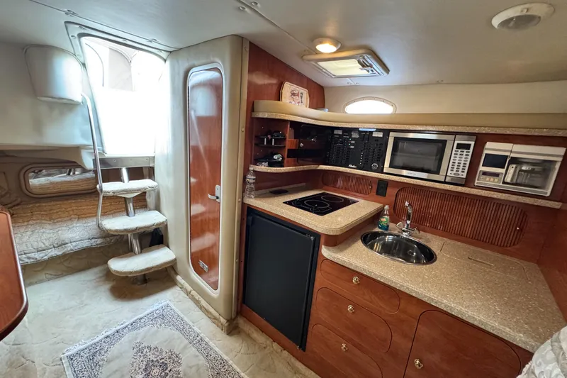 Slide: The Image of 2005 Rinker Fiesta Vee 342 interior with kitchenette, stairs, and cozy sleeping area. - 28