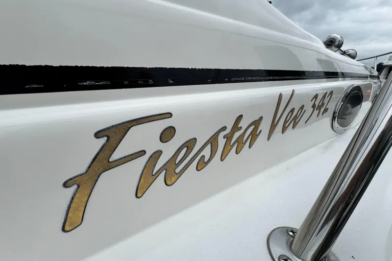 Slide: The Image of 2005 Rinker Fiesta Vee 342 boat nameplate with gold lettering on white hull. - 7