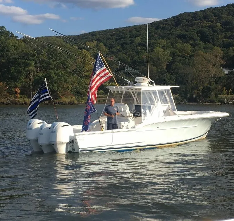 Slide: The Image of 2017 Buddy Davis 34 Center Console boat with flags on a scenic lake. - 3