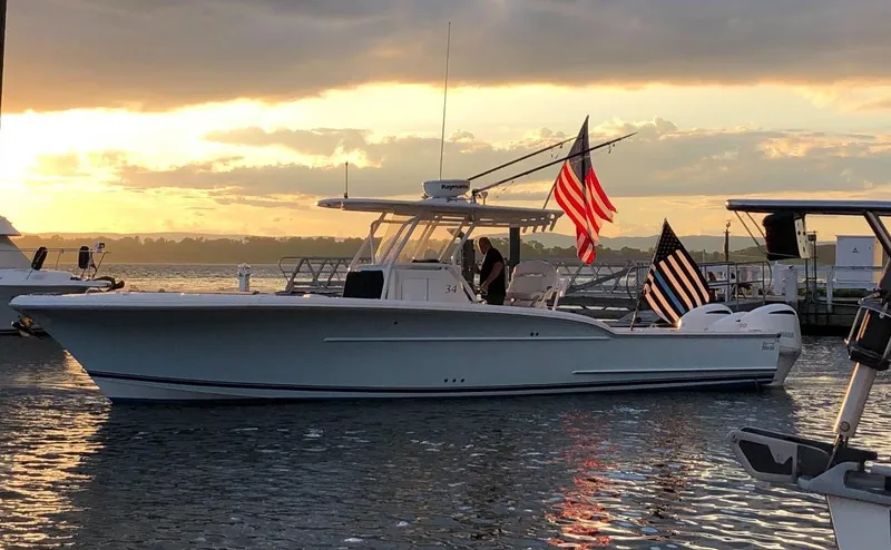Slide: The Image of 2017 Buddy Davis 34 Center Console boat at sunset with flags, docked in calm waters. - 4