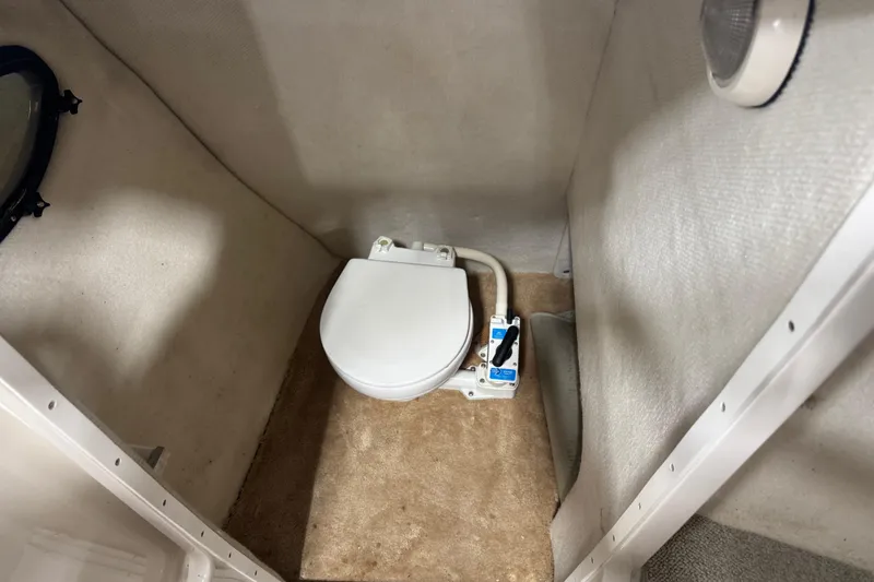 Slide: The Image of 1998 Regal 2800 LSR boat interior with compact marine toilet and beige carpeting. - 10