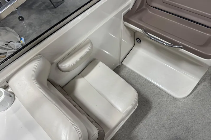 Slide: The Image of Interior seating of a 1998 Regal 2800 LSR boat, featuring white upholstery and a cup holder. - 6