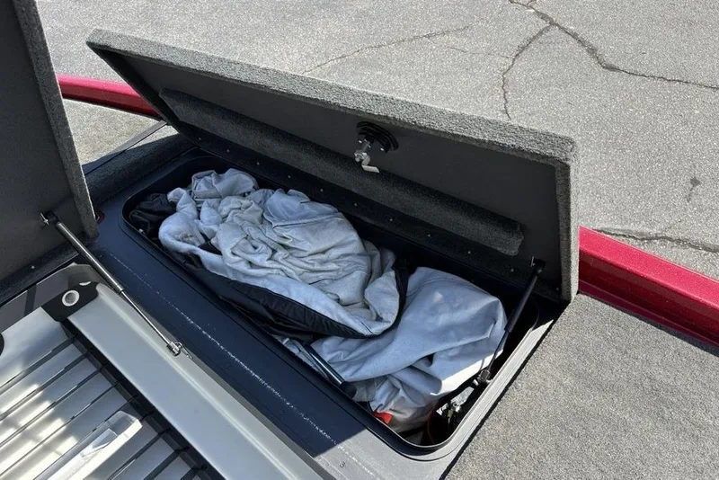 Slide: The Image of Open storage compartment in a 2015 Skeeter ZX225 boat with clothes inside. - 13