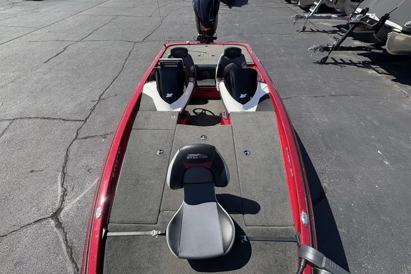 Slide: The Image of 2015 Skeeter ZX225 bass boat with red trim and seating, parked on pavement. - 25