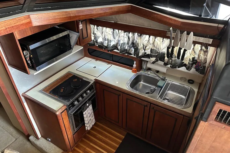 Slide: The Image of 1994 Bayliner 3888 Motoryacht kitchen with stove, sink, microwave, and knife set. - 12