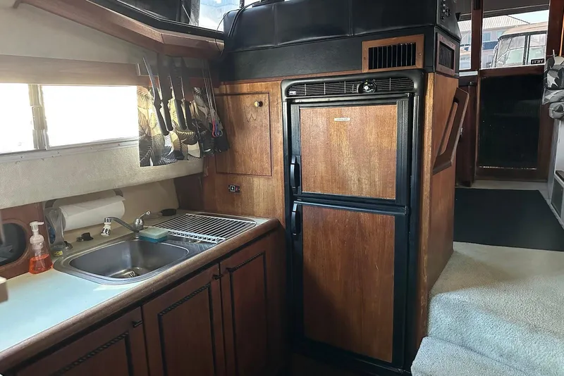 Slide: The Image of 1994 Bayliner 3888 Motoryacht kitchen with wooden cabinets, sink, and refrigerator. - 21