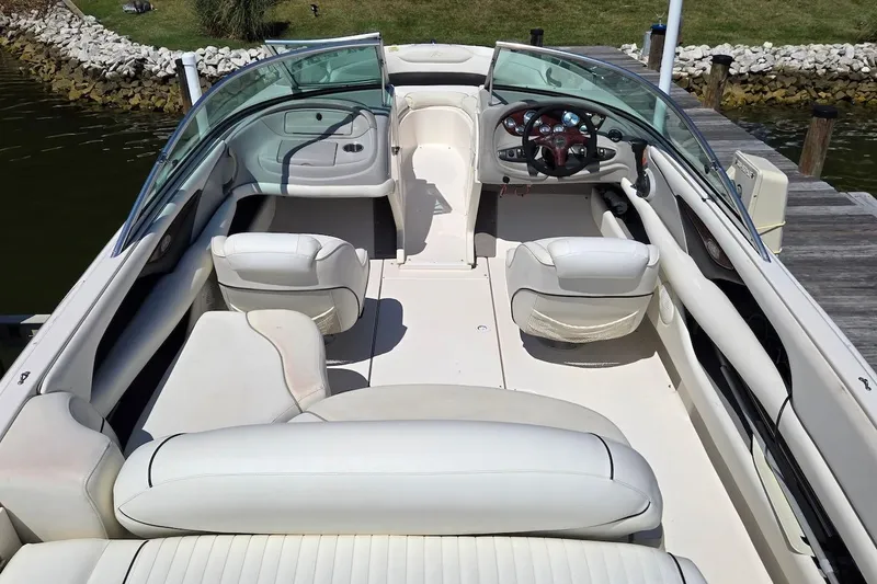 Slide: The Image of 2003 Monterey 228SI Montura Bowrider with white interior, docked by a grassy shoreline. - 9