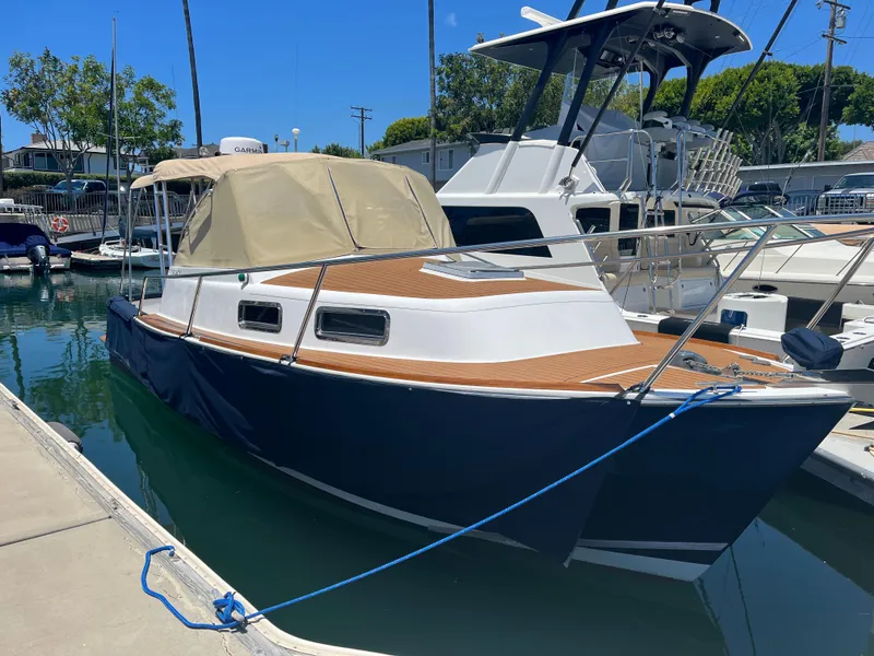 The Image of 2001 Legacy Yachts 28 Express docked in a marina, featuring a blue hull and tan canopy. - 0