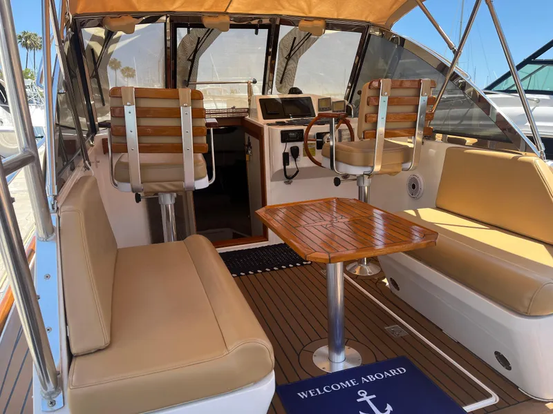 Slide: The Image of Interior of 2001 Legacy Yachts 28 Express with seating and helm, featuring a "Welcome Aboard" mat. - 11