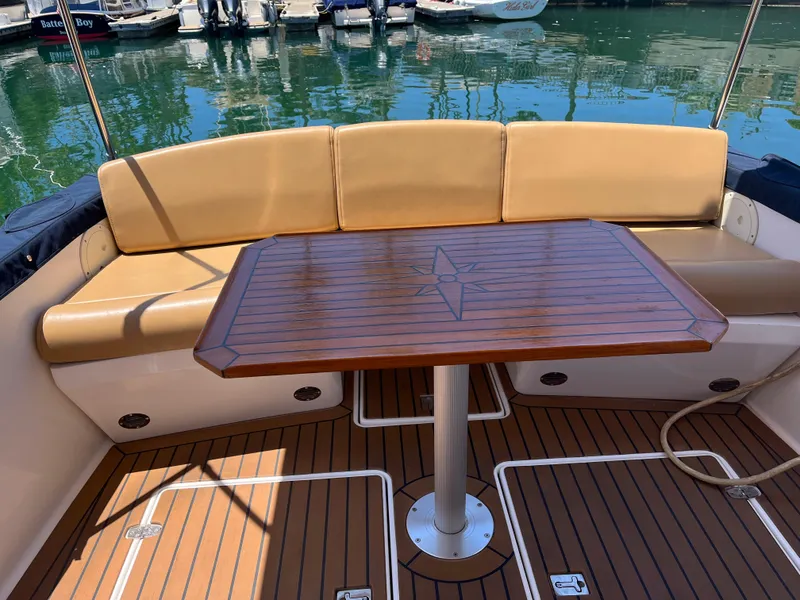 Slide: The Image of 2001 Legacy Yachts 28 Express interior with wooden table and cushioned seating. - 13