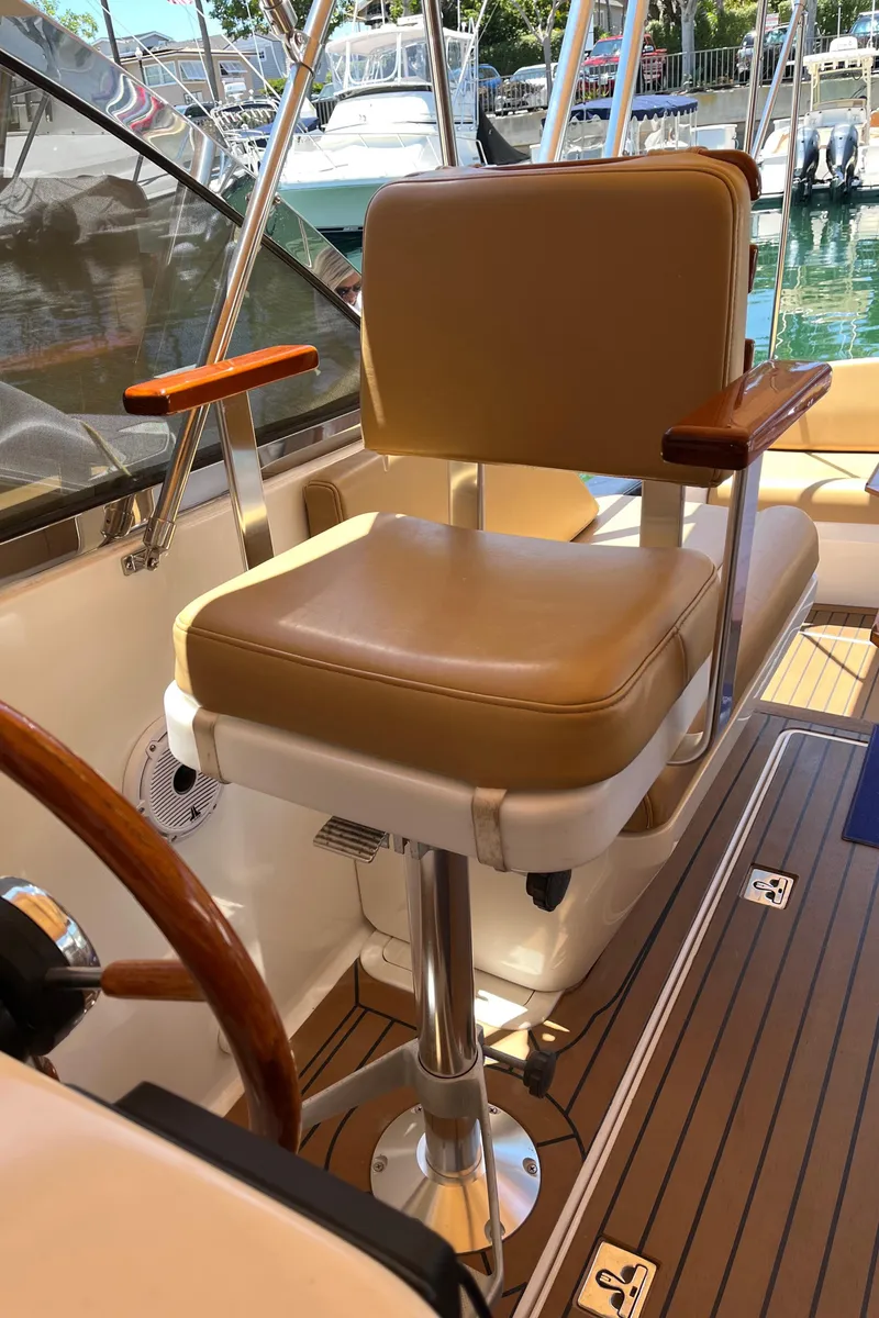 Slide: The Image of Captain's chair on 2001 Legacy Yachts 28 Express, featuring tan upholstery and wooden accents. - 15