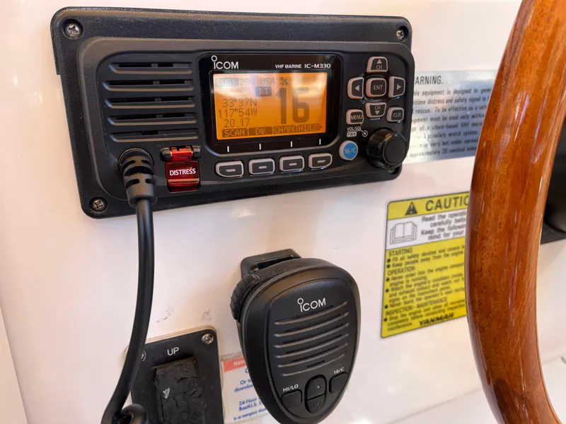 Slide: The Image of ICOM marine radio on 2001 Legacy Yachts 28 Express dashboard with microphone and warning labels. - 19