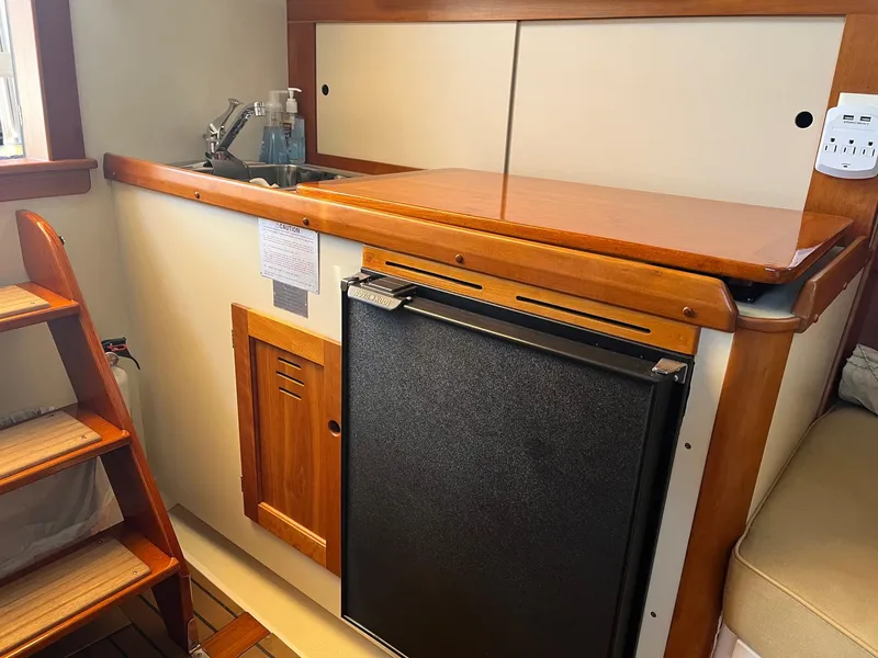 Slide: The Image of 2001 Legacy Yachts 28 Express interior with kitchenette, featuring sink and compact fridge. - 2