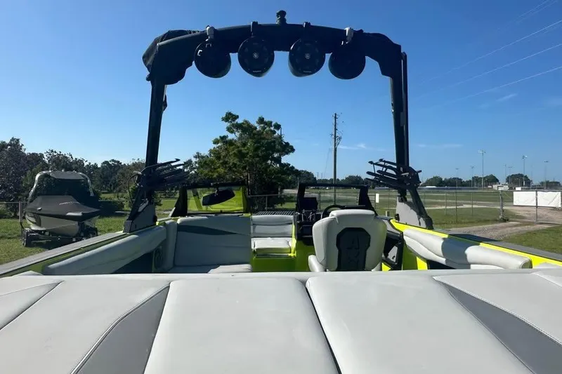 Slide: The Image of 2023 Axis A225 boat interior with seating and wakeboard tower, parked outdoors. - 12