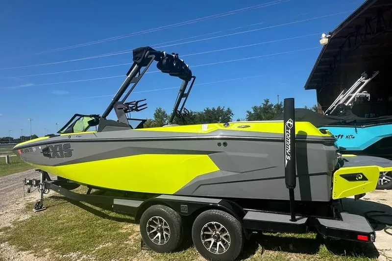 Slide: The Image of 2023 Axis A225 boat in vibrant yellow and gray on a trailer, outdoors. - 2