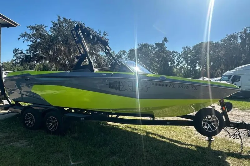 Slide: The Image of 2023 Axis A225 boat in vibrant green and gray, parked on a trailer in sunlight. - 3