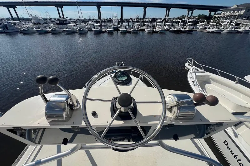 Slide: The Image of Helm of 1998 Henriques 28 Express boat overlooking marina with bridge in background. - 11