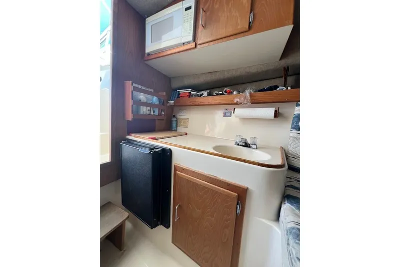 Slide: The Image of 1998 Henriques 28 Express boat interior with kitchenette, featuring sink, microwave, and storage cabinets. - 9