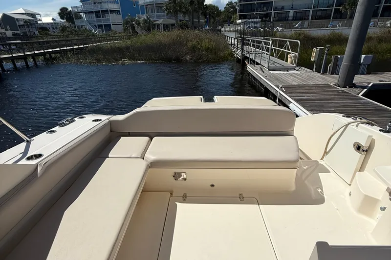 Slide: The Image of 2013 Pursuit SC 365i Sport Coupe boat interior with beige seating at a dock. - 10