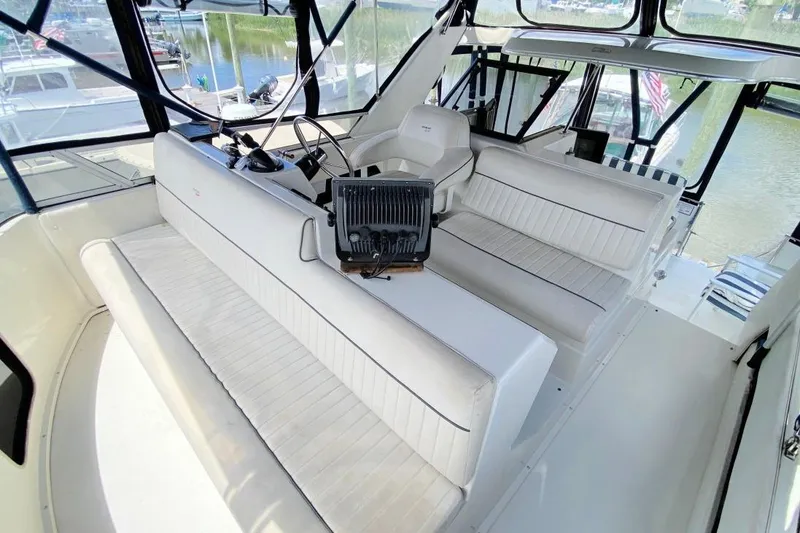 Slide: The Image of 1992 Carver 36 Aft Cabin interior with white seating and helm, docked at marina. - 10
