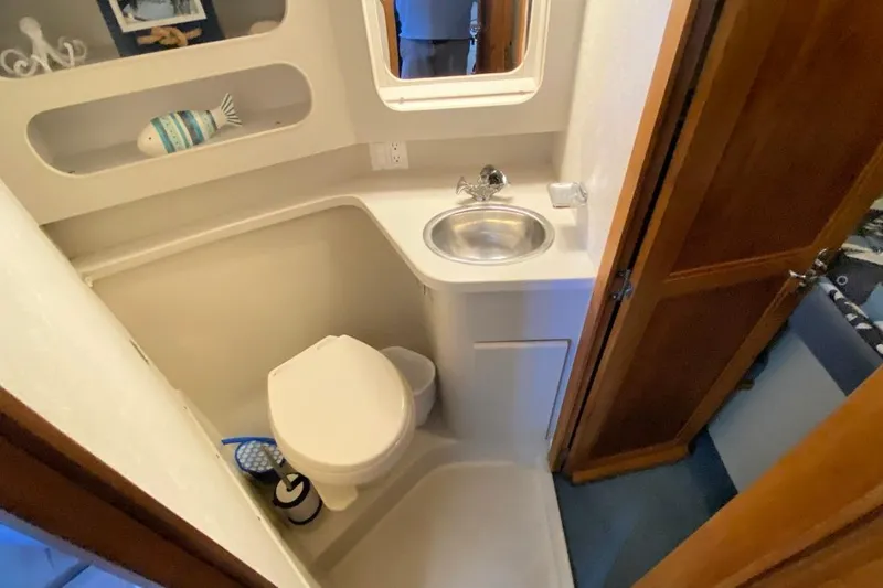 Slide: The Image of 1992 Carver 36 Aft Cabin bathroom with sink, toilet, and decorative fish. - 21