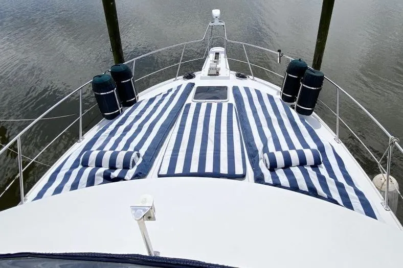 Slide: The Image of 1992 Carver 36 Aft Cabin yacht with striped deck cushions, docked on calm water. - 11