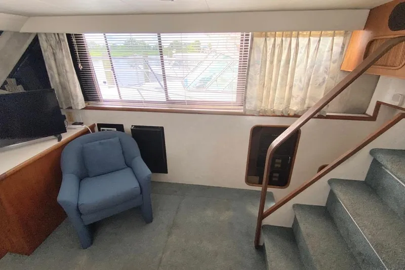 Slide: The Image of 1992 Carver 36 Aft Cabin interior with blue armchair, stairs, and window view. - 19