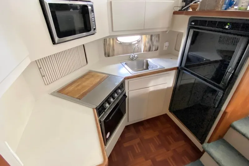 Slide: The Image of 1992 Carver 36 Aft Cabin kitchen with stove, sink, microwave, and refrigerator. - 5