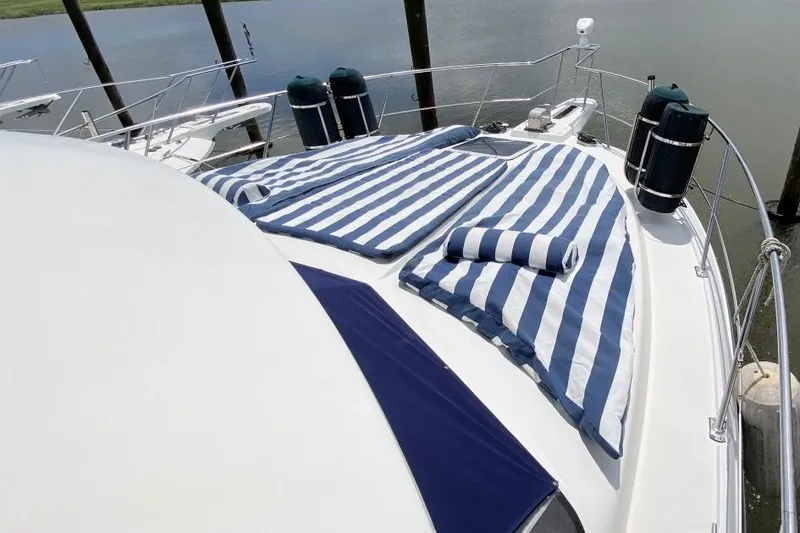Slide: The Image of 1992 Carver 36 Aft Cabin yacht with striped sun pads on deck, docked by the water. - 9
