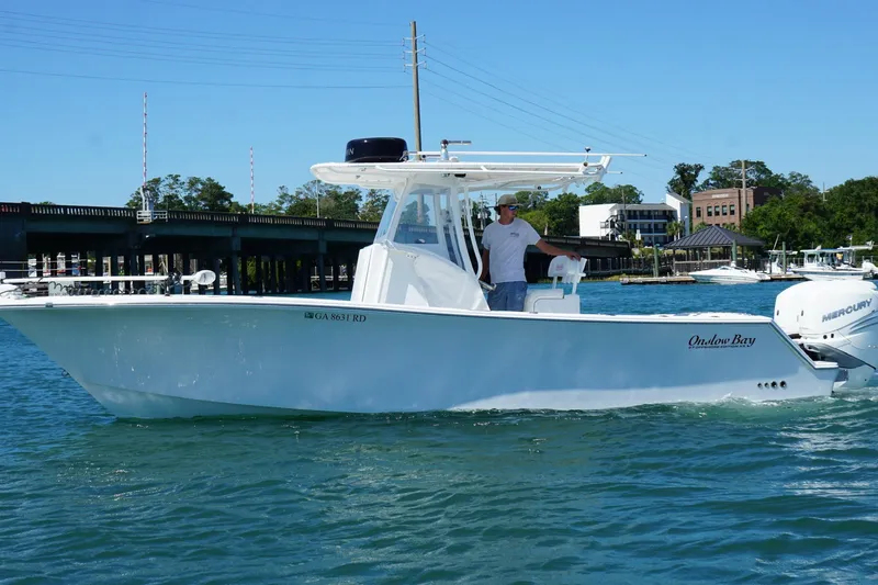Slide: The Image of 2016 Onslow Bay 27 XS boat cruising on a sunny day near a bridge. - 3