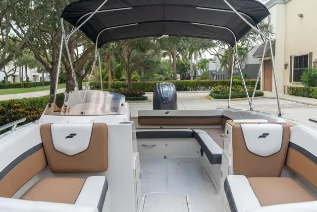 Slide: The Image of 2026 Starcraft SVX 211 OB boat interior with seating and canopy, parked outdoors. - 9