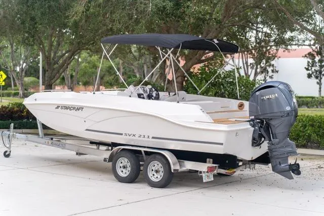 Slide: The Image of 2026 Starcraft SVX 211 OB boat on trailer, parked outdoors with Yamaha outboard motor. - 2