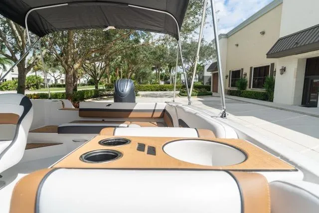 Slide: The Image of 2026 Starcraft SVX 211 OB boat interior with seating and cup holders, parked outdoors. - 16