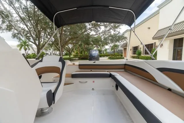 Slide: The Image of 2026 Starcraft SVX 211 OB boat interior with seating and canopy, parked outdoors. - 10