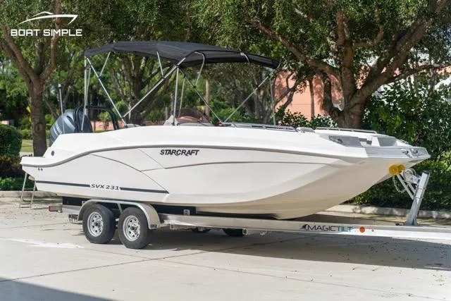 Slide: The Image of 2023 Starcraft SVX 231 OB DH boat on trailer, parked outdoors. - 2